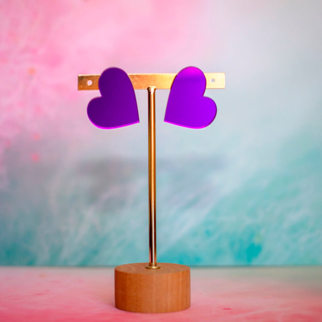 Pendientes corazón morados de metacrilato brillante sobre fondo claro